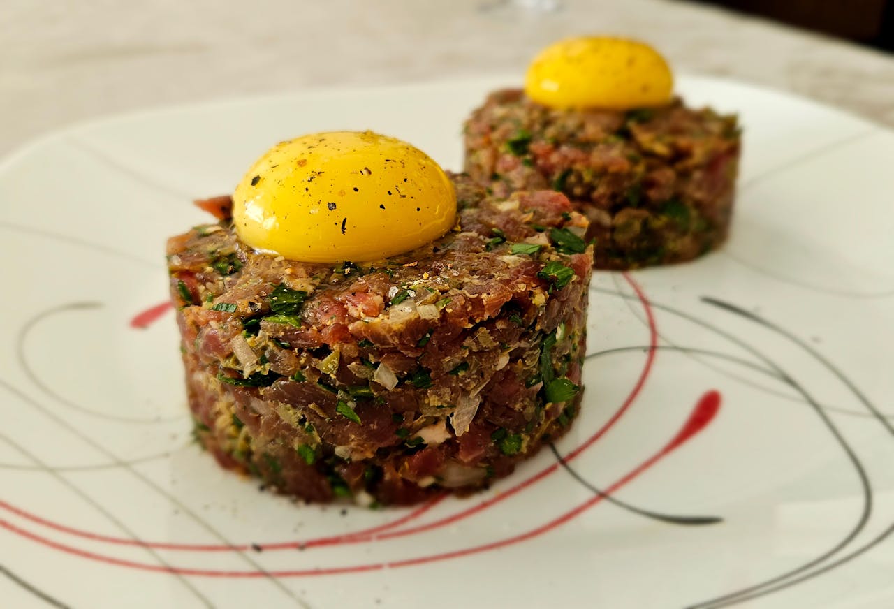 home-hero Savory beef tartare topped with fresh egg yolk on an elegant plate.
